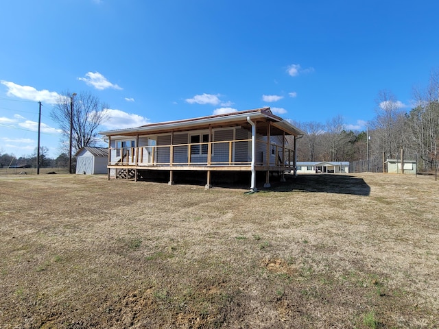 rear view of house featuring a deck, a shed, and a lawn