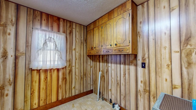 washroom featuring a textured ceiling and wood walls