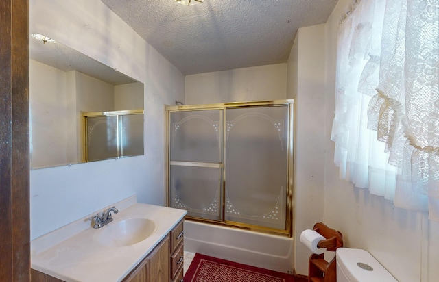 full bathroom with vanity, a textured ceiling, shower / bath combination with glass door, and toilet