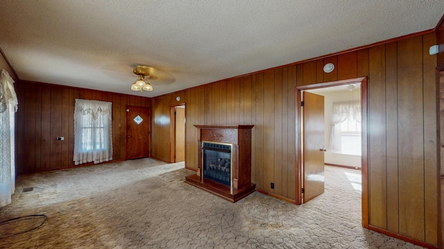 unfurnished living room with light carpet, a textured ceiling, a fireplace, and a healthy amount of sunlight