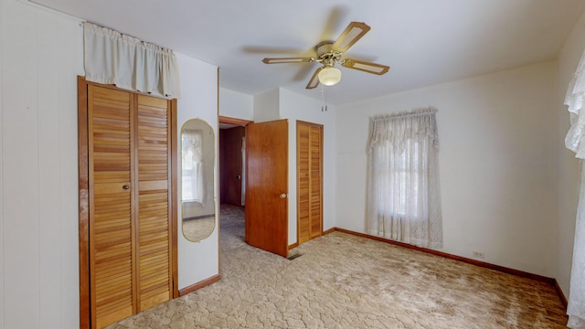 unfurnished bedroom with multiple closets, light colored carpet, and ceiling fan