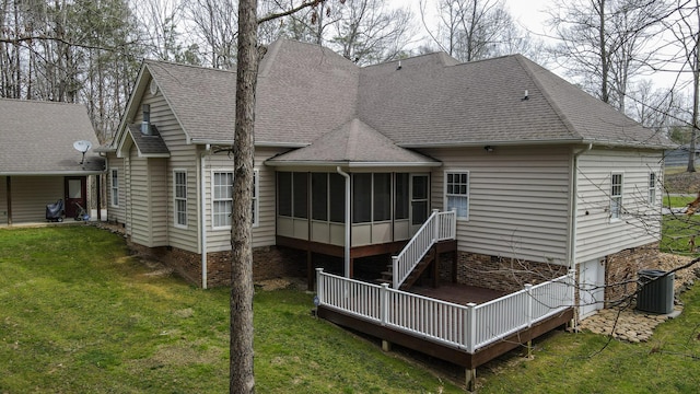 rear view of house with central AC, roof with shingles, a yard, and a sunroom