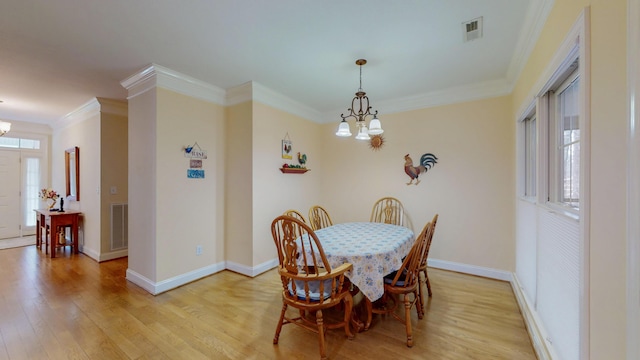 dining room with light wood-style flooring, crown molding, and an inviting chandelier