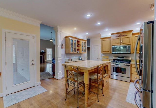 kitchen with appliances with stainless steel finishes, light countertops, light wood-style floors, and crown molding