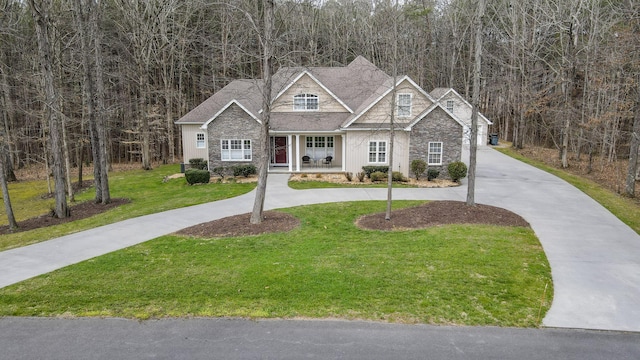 view of front of home with stone siding, curved driveway, and a front yard