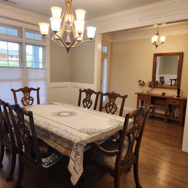 dining space featuring a wainscoted wall, dark wood-type flooring, an inviting chandelier, and crown molding