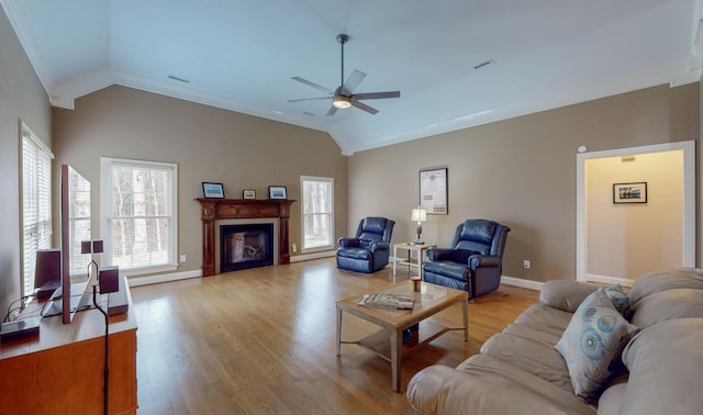 living area featuring vaulted ceiling, a fireplace, light wood finished floors, and ceiling fan