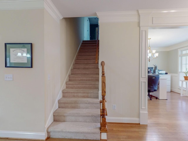 staircase featuring washer / clothes dryer, wood finished floors, an inviting chandelier, crown molding, and baseboards