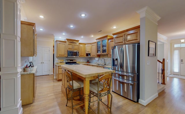 kitchen with crown molding, appliances with stainless steel finishes, wood counters, and a sink