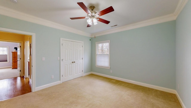 unfurnished bedroom with visible vents, multiple windows, ornamental molding, and carpet flooring