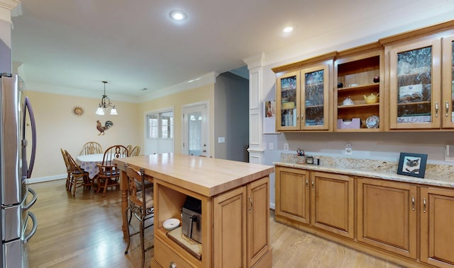 kitchen with light wood finished floors, freestanding refrigerator, wood counters, crown molding, and decorative light fixtures