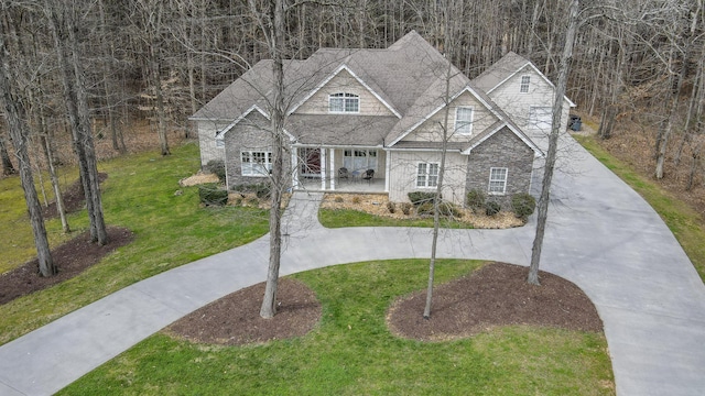 view of front of property featuring a front lawn, stone siding, and driveway