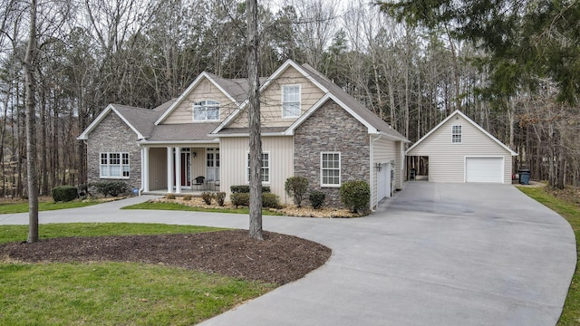 craftsman-style home with a garage, stone siding, covered porch, and concrete driveway