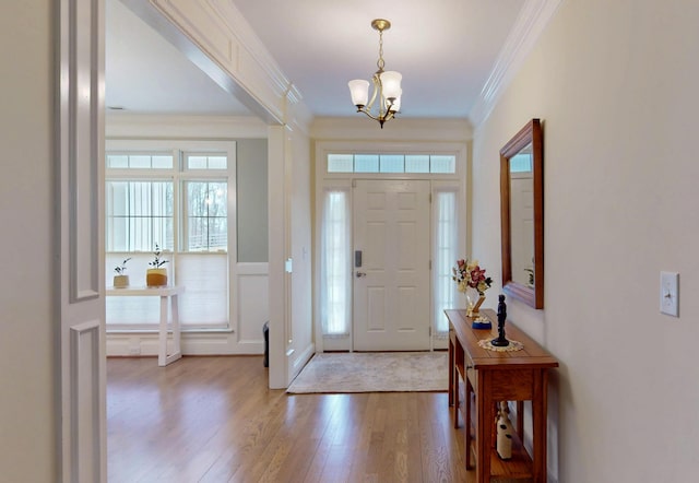 entrance foyer featuring light wood-type flooring, an inviting chandelier, and crown molding