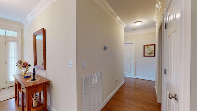 hall featuring crown molding, light wood-style flooring, baseboards, and visible vents