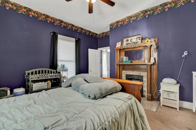 carpeted bedroom featuring a fireplace and ceiling fan