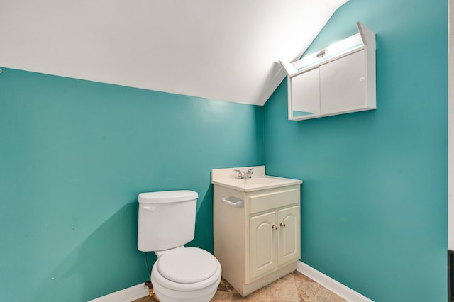 bathroom with vanity, vaulted ceiling, tile patterned flooring, and toilet