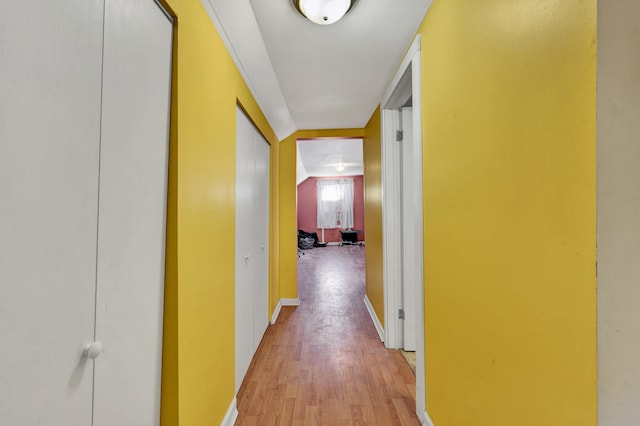 corridor featuring light hardwood / wood-style floors and lofted ceiling