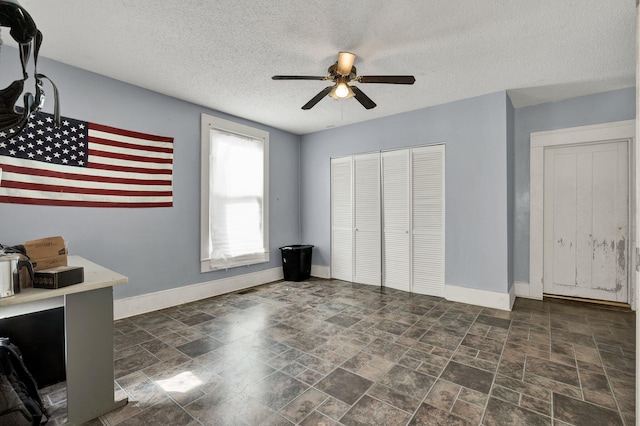 unfurnished bedroom with a textured ceiling, a closet, and ceiling fan