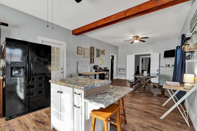 kitchen with light stone countertops, a textured ceiling, hardwood / wood-style flooring, black fridge, and ceiling fan