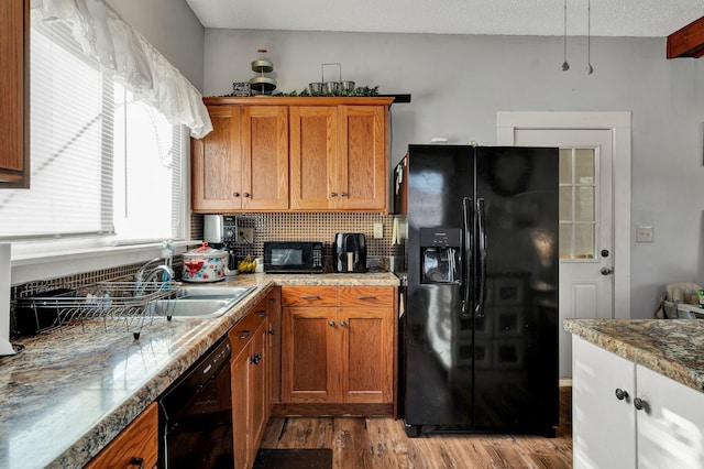 kitchen featuring black appliances, light wood-type flooring, and backsplash