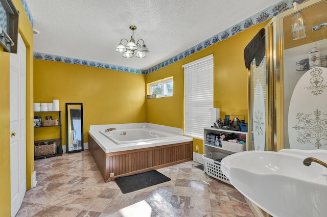 bathroom with a textured ceiling, an inviting chandelier, and a bath