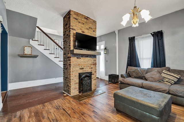 living room with a fireplace, wood-type flooring, a textured ceiling, and an inviting chandelier