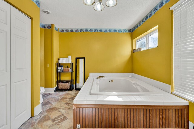 bathroom featuring a textured ceiling, toilet, and a bathing tub