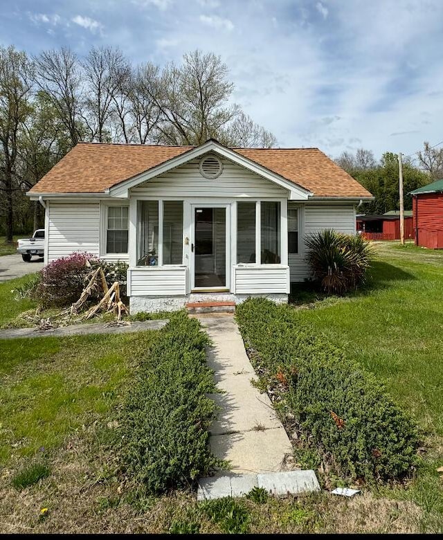 view of front of house with a front yard and a sunroom