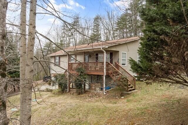 rear view of property with a wooden deck and a yard