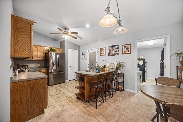 kitchen featuring pendant lighting, ceiling fan, range, stainless steel fridge with ice dispenser, and vaulted ceiling