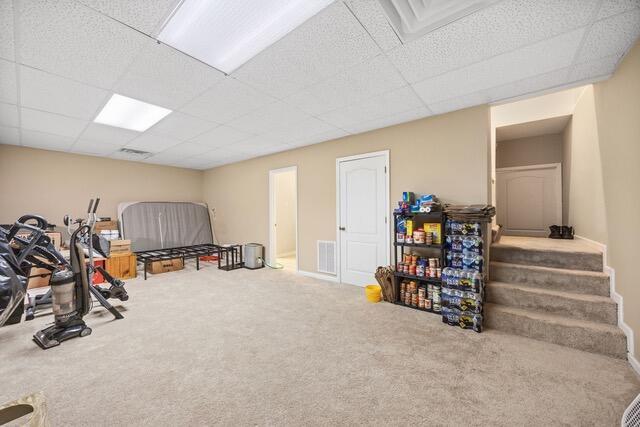 exercise area featuring carpet floors and a drop ceiling