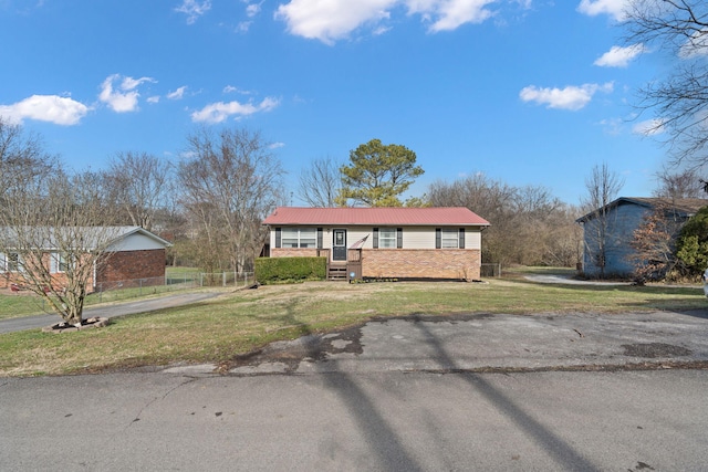 ranch-style home featuring a front yard, metal roof, and fence