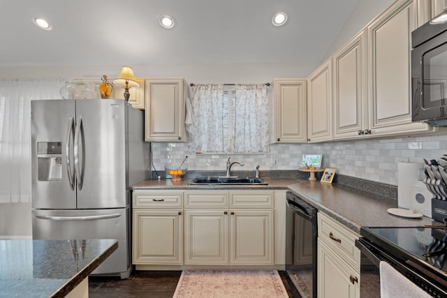 kitchen featuring tasteful backsplash, sink, dark stone countertops, black appliances, and cream cabinetry