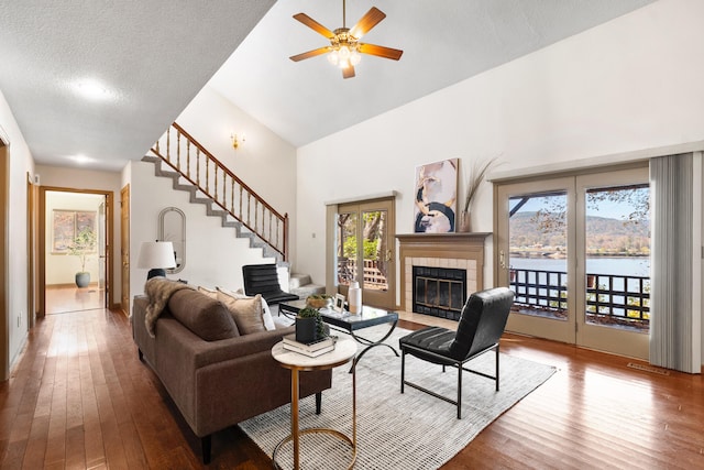 living room featuring a textured ceiling, ceiling fan, a water view, high vaulted ceiling, and hardwood / wood-style floors