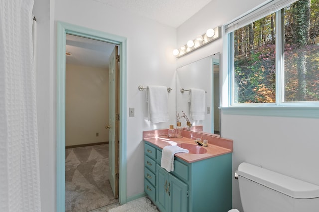 bathroom featuring plenty of natural light, vanity, a textured ceiling, and toilet