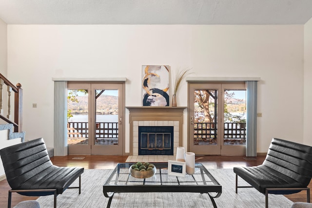 living room featuring a tile fireplace, a textured ceiling, hardwood / wood-style flooring, and a wealth of natural light