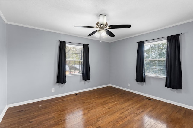 empty room featuring visible vents, baseboards, crown molding, and hardwood / wood-style flooring