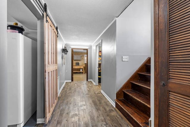 hallway with baseboards, stairs, dark wood-type flooring, a textured ceiling, and a barn door