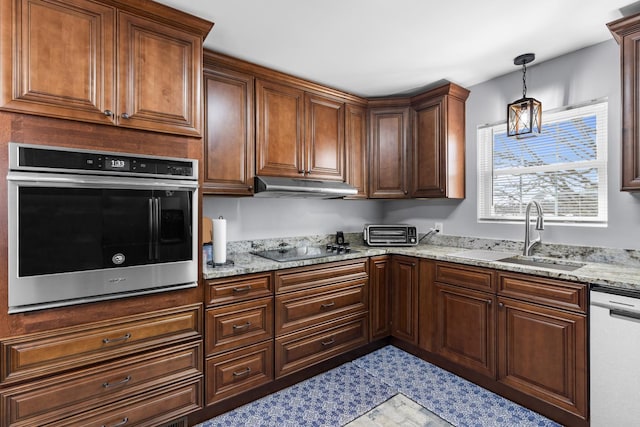 kitchen with a sink, stainless steel appliances, light stone counters, and under cabinet range hood