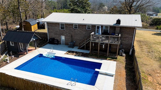 outdoor pool featuring stairs, an outdoor structure, a deck, a patio, and a diving board