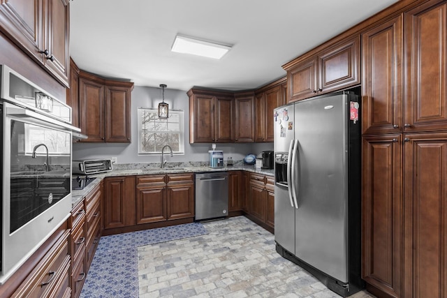 kitchen featuring a sink, decorative light fixtures, light stone countertops, and stainless steel appliances