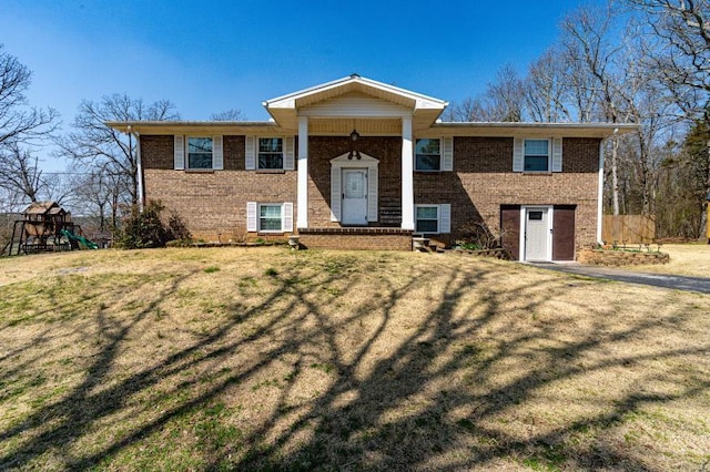 split foyer home featuring brick siding, a playground, and a front lawn