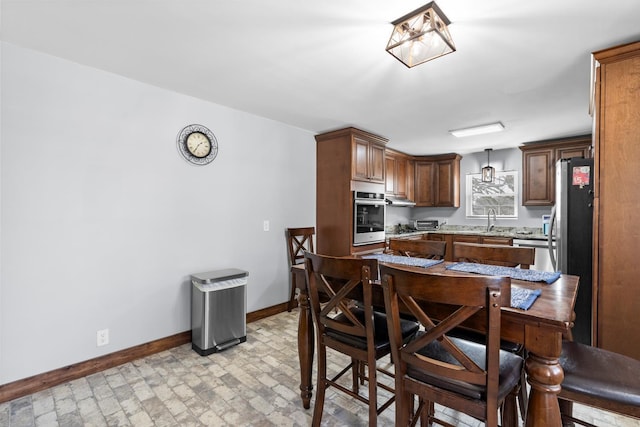 dining room featuring brick floor and baseboards