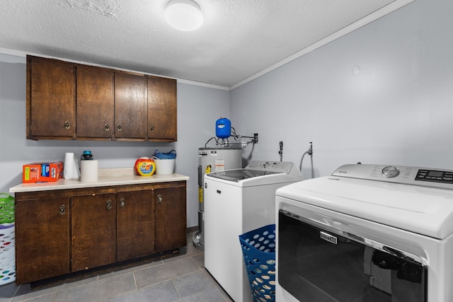 washroom featuring cabinet space, water heater, a textured ceiling, crown molding, and washer and clothes dryer