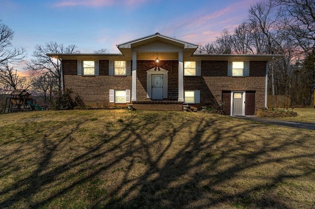 split foyer home with a yard, brick siding, and a playground