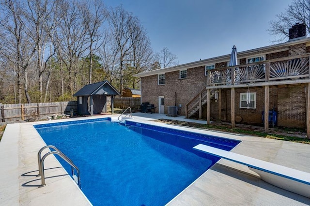 view of pool featuring stairs, cooling unit, a fenced backyard, an outbuilding, and a patio