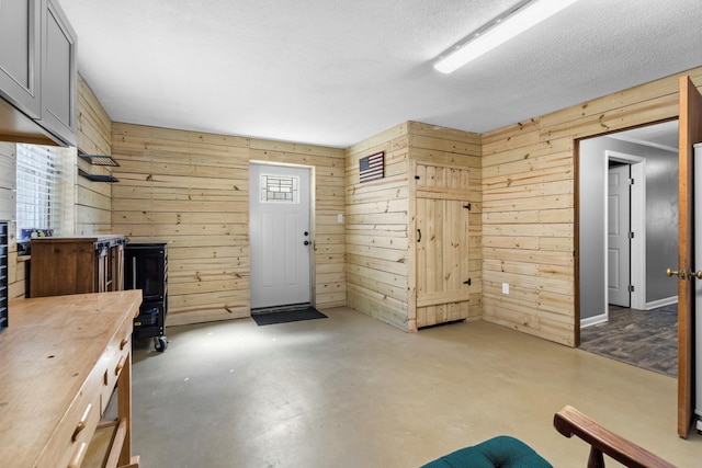 interior space with a textured ceiling, finished concrete flooring, and wood walls