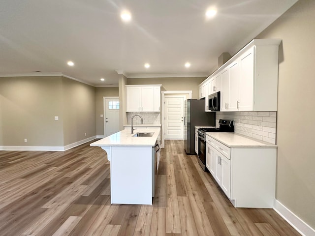 kitchen with decorative backsplash, appliances with stainless steel finishes, sink, a center island with sink, and white cabinets