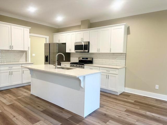 kitchen with a center island with sink, sink, light stone countertops, white cabinetry, and stainless steel appliances